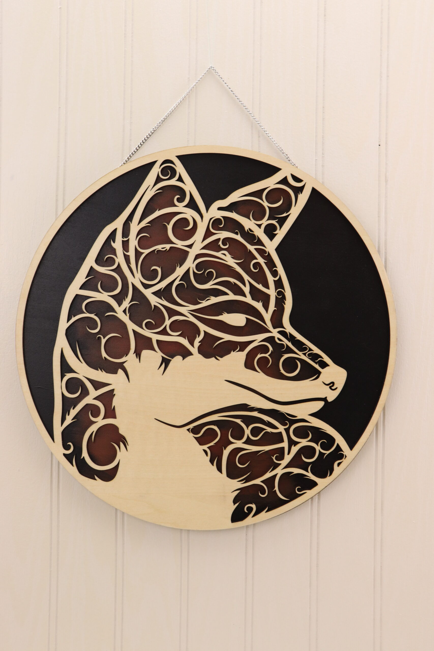 Fox Door Sign This fox door sign is laser cut with fine, intricate swirl details that form together into the shape of a fox head. The background is hand painted in in black and fox red allowing the unfinished wood detail of the fox and outer border to shine.