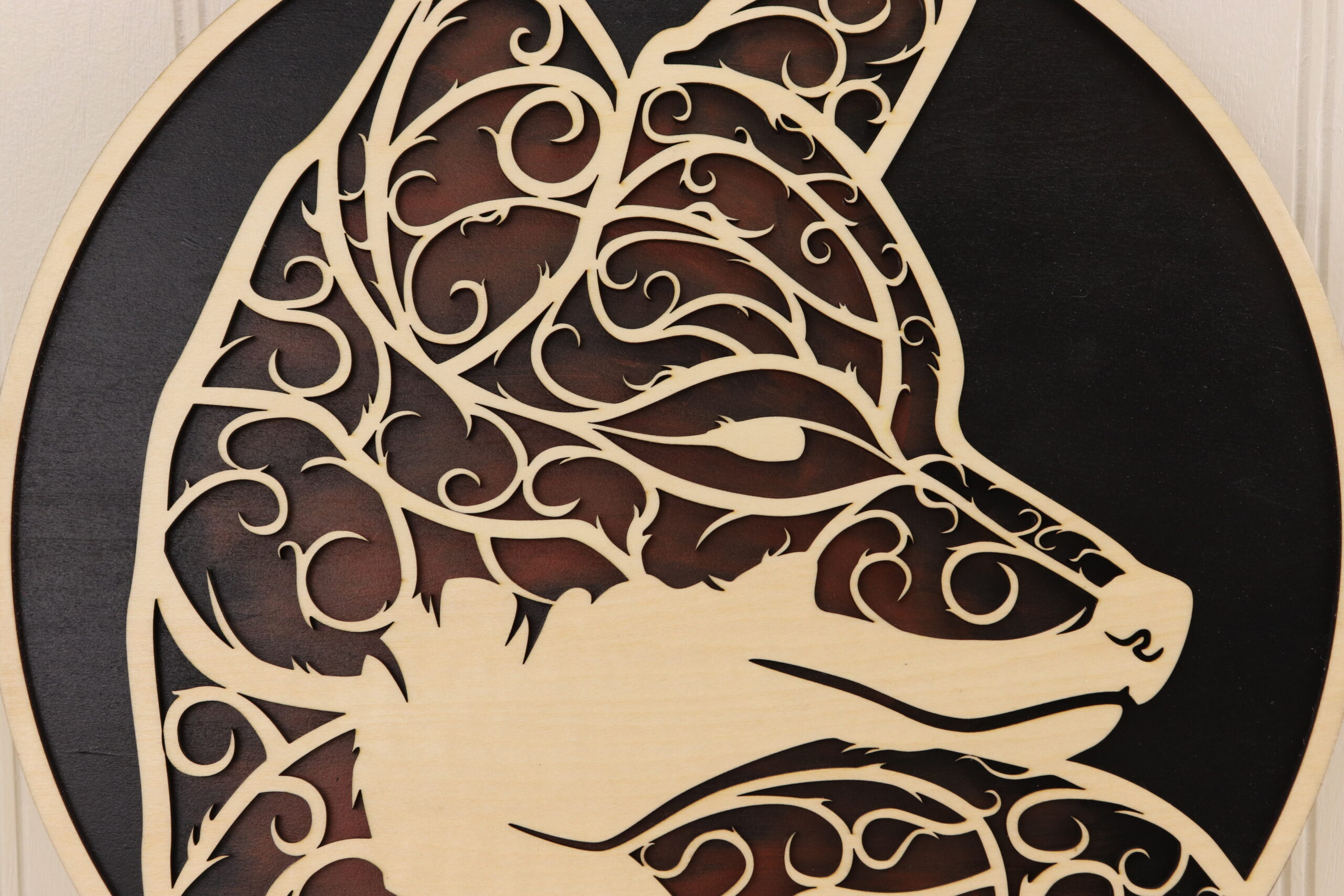 This fox door sign is laser cut with fine, intricate swirl details that form together into the shape of a fox head. The background is hand painted in in black and fox red allowing the unfinished wood detail of the fox and outer border to shine.